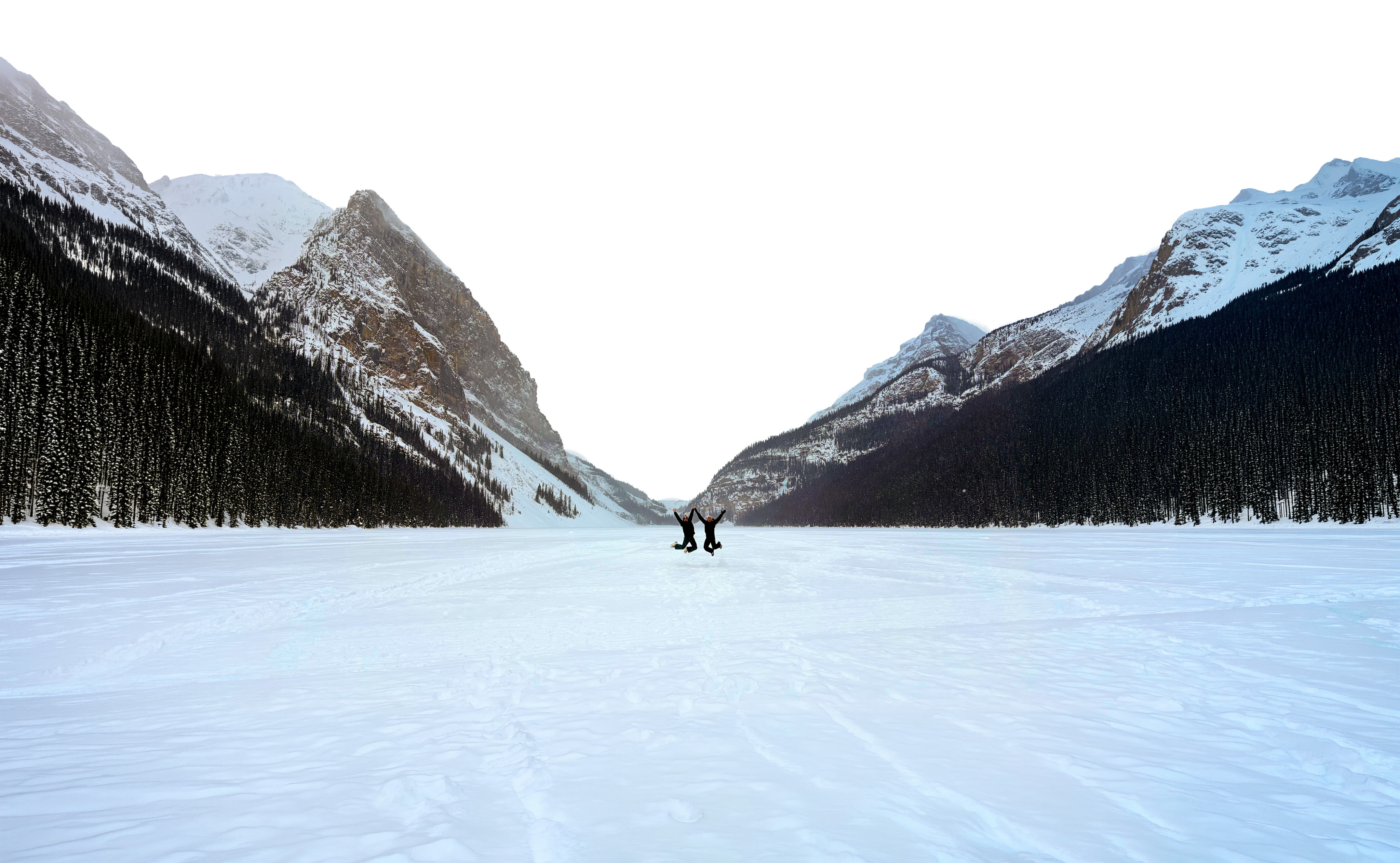 Image of Jason and Lorence at Lake Louise, jumping in unison on the frozen lake with soaring mountains behind them