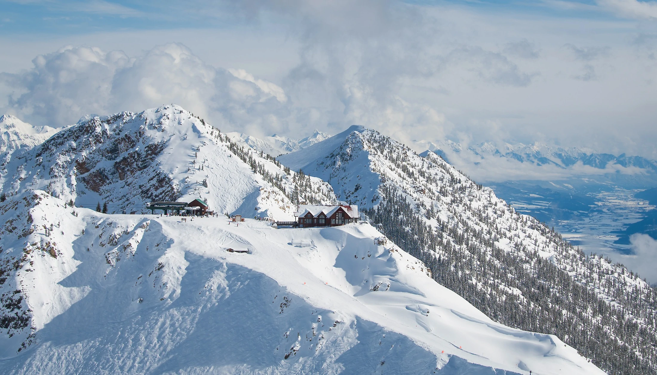 Aerial view of mountain top restaurant showcasing snowy mountains on a clear sunny day